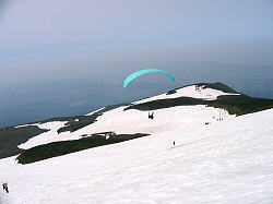 雪渓最上部からパラグライダーが飛び立つ